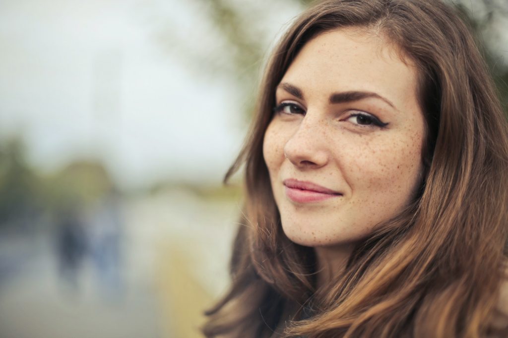 Freckled woman with long hair smiling